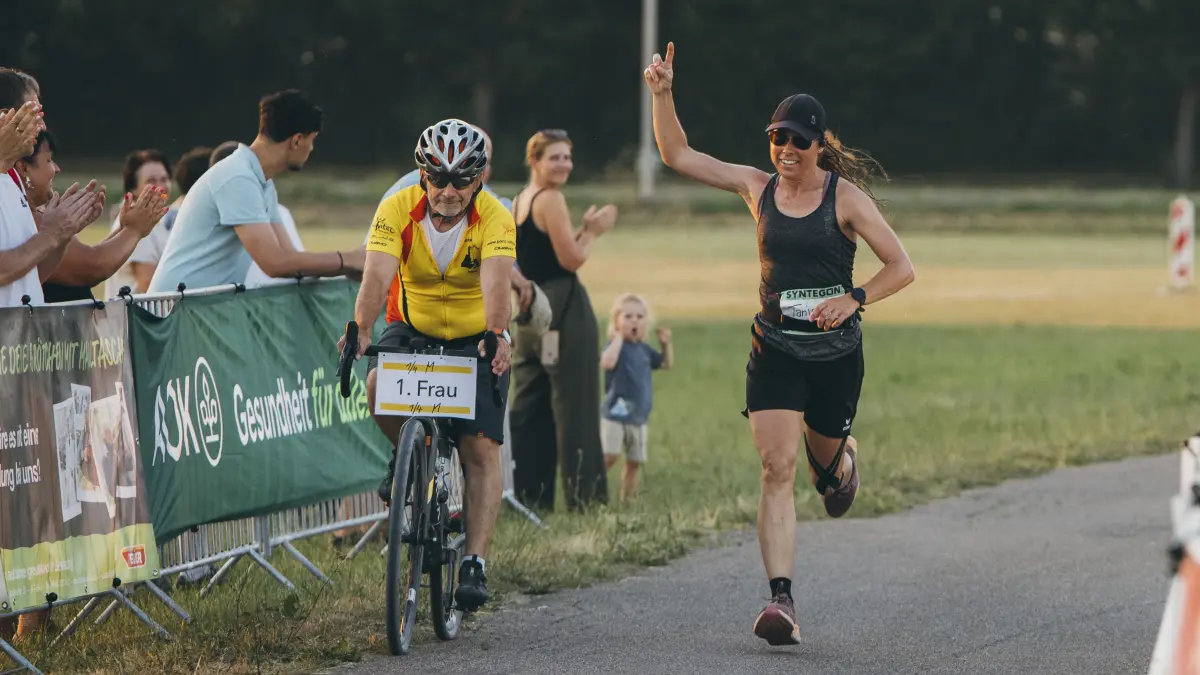 Tanja Schienagel beendet den Burgberglauf, der auch zum Vier-Jahreszeiten-Laufcup gehört, in diesem Jahr als erste Frau. Das Schild des Begleitfahrradfahrers verkündet ihre Position.
