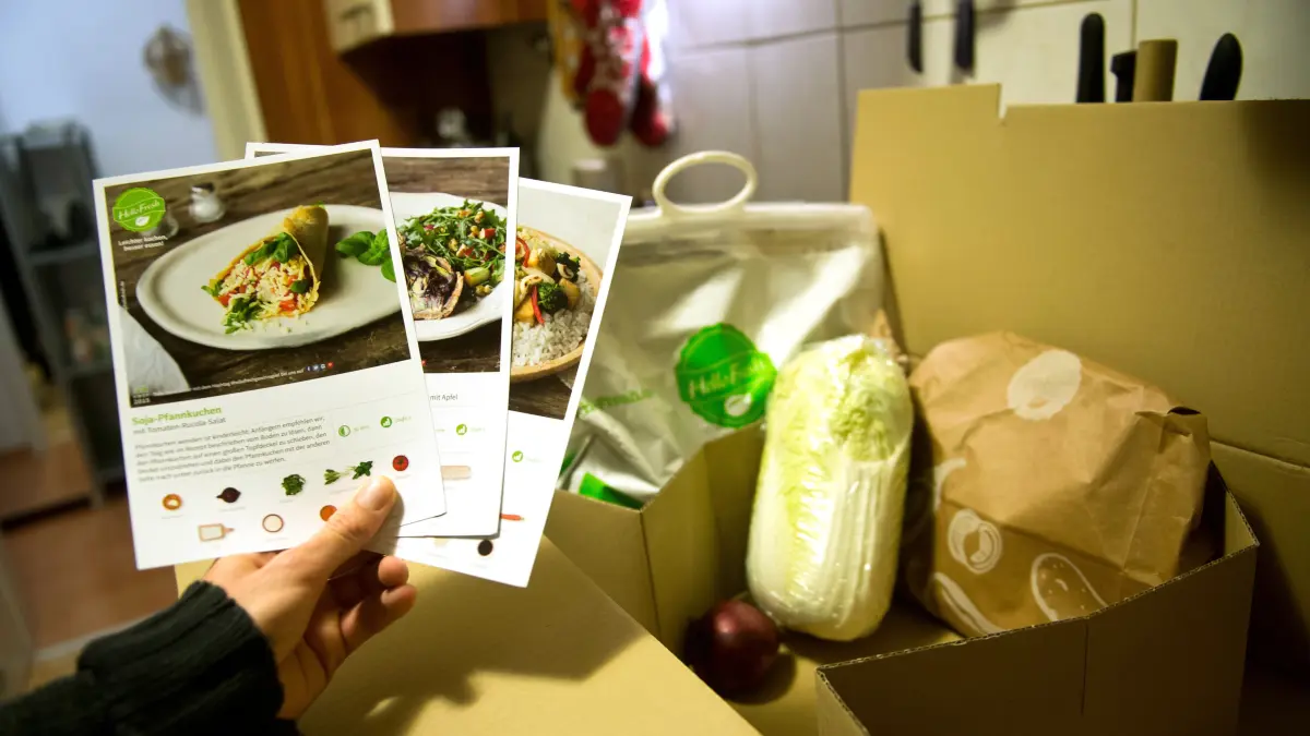 ILLUSTRATION - Ein Mann hält mitgelieferte Kochrezepte aus einer HelloFresh Kochbox in der Hand. (zu dpa «Hellofresh trotzt Restaurant-Konkurrenz und legt Umsatzsprung hin») +++ dpa-Bildfunk +++