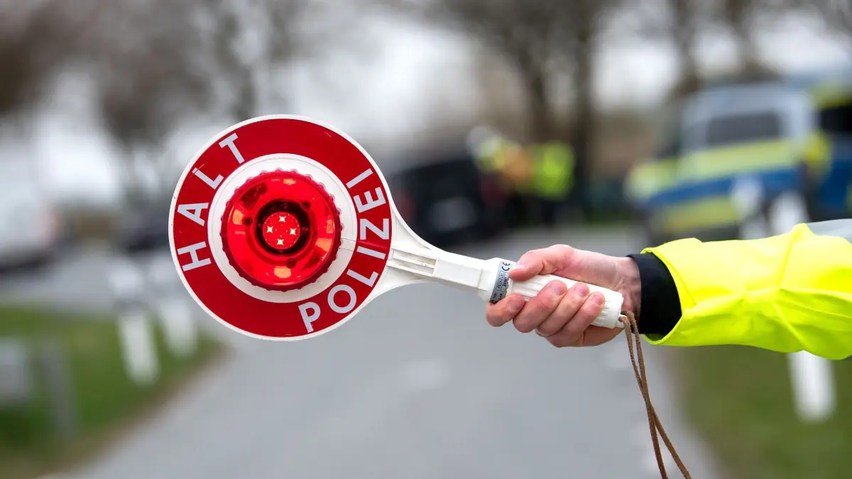 Verkehrskontrolle: ILLUSTRATION - 13.04.2026, Schleswig-Holstein, Heide: Ein Beamter hält eine "Polizeikelle" mit der Aufschrift "Halt Polizei" in die Luft. (Symbolbild) (zu dpa: «Fahrer flüchtet vor Kontrolle - vier Autos im Straßengraben») Foto: Daniel Bockwoldt/dpa +++ dpa-Bildfunk +++