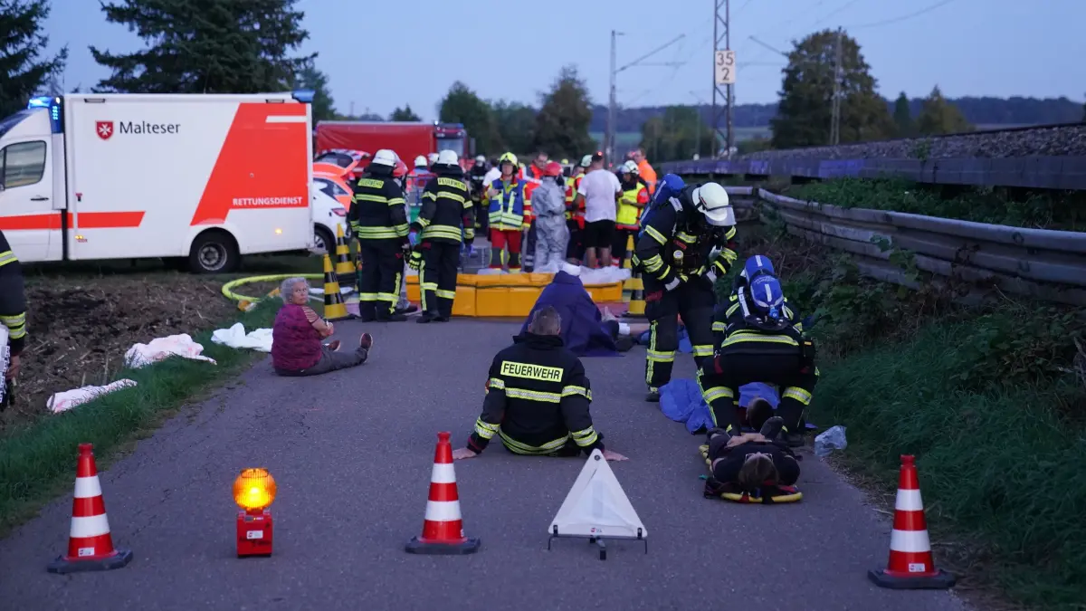 Kreis Goeppingen: Einsatzkraefte proben Kerosin-Austritt aus Pipeline:
Ein Leck an einer Treibstoffpipeline, austretendes Kerosin und mehrere Verletzte: Mit einem aufwendigen Schadensszenario haben zahlreiche Einsatzkraefte am Mittwoch im Landkreis Goeppingen fuer einen moeglichen Ernstfall geuebt. Feuerwehren aus zahlreichen Kommunen, Rettungsdienst, Technisches Hilfswerk und Spezialkraefte waren an der gross angelegten Uebung beteiligt.<br />
<br />
Das angenommene Szenario hatte es in sich: Bei Arbeiten an der durch den Landkreis verlaufenden Pipeline war es zu einer Beschaedigung der Leitung gekommen. Kerosin trat aus, mehrere Arbeiter befanden sich im Gefahrenbereich und mussten gerettet werden. Gleichzeitig bestand die Gefahr, dass der ausgetretene Kraftstoff ueber das Gelaende und angrenzende Gewaesser weitergetragen wird.<br />
<br />
„Wir haben im Landkreis Goeppingen eine Pipeline, die quer durch unseren Landkreis verlaeuft“, erklaerte Kreisbrandmeister Prof. Dr.-Ing. Michael Reick. Ueber die Leitung wuerden Kerosin beziehungsweise Mineraloelprodukte transportiert. Komme es zu einer Leckage, bestehe eine der ersten Aufgaben der Feuerwehren darin, die Austrittsstelle ueberhaupt zu lokalisieren.<br />
<br />
Rund 100 Kraefte suchen Pipeline nach Leck ab<br />
<br />
Dazu wurden bei der Uebung zahlreiche Feuerwehren als Suchtrupps entlang der Pipeline eingesetzt. Rund 100 Einsatzkraefte waren nach Angaben des Kreisbrandmeisters unterwegs, um die Strecke mit ihren Fahrzeugen abzufahren beziehungsweise abzugehen und die angenommene Leckage moeglichst schnell zu finden.<br />
<br />
Beteiligt waren unter anderem die Feuerwehren aus Schlierbach, Albershausen, Uhingen, Ebersbach, Rechberghausen, Wangen, Birenbach, Boertlingen und Waeschenbeuren. Damit erstreckte sich die Uebung ueber einen grossen Bereich des Landkreises.<br />
<br />
Nachdem die angenommene Schadensstelle lokalisiert worden war, galt es vor allem, den weiteren Austritt des Kraftstoffs zu begrenzen und die Auswirkungen auf die Umwelt so gering wie moeglich zu halten.<br />
<br />
Fuenf vorbereitete Oelsperren im Landkreis<br />
<br />
Eine wichtige Rolle spielte dabei der Gewaesserschutz. An insgesamt fuenf vorbereiteten Stellen wurden Oelsperren eingesetzt. Sie sollen im Ernstfall verhindern, dass ausgetretenes Kerosin oder andere Mineraloelprodukte ungehindert ueber Baeche weitertransportiert werden.<br />
<br />
Die Einsatzkraefte trainierten damit nicht nur die direkte Arbeit an einer beschaedigten Pipeline, sondern gleichzeitig die Massnahmen, die kilometerweit von der eigentlichen Leckage entfernt notwendig werden koennen.<br />
<br />
Acht Verletzte muessen gerettet und dekontaminiert werden<br />
<br />
Parallel dazu wurde eine groessere rettungsdienstliche Lage simuliert. Nach Uebungsannahme hatten sich bei Reparaturarbeiten mehrere Mitarbeiter unmittelbar im Bereich der Pipeline befunden.<br />
<br />
Insgesamt acht Beschaeftigte der Pipelinegesellschaft galten als verletzt. Die Feuerwehr Uhingen musste die Personen zunaechst aus dem Gefahrenbereich retten. Anschliessend wurden sie dekontaminiert, um anhaftendes Kerosin zu entfernen, bevor sie an den Rettungsdienst uebergeben werden konnten.<br />
<br />
Die angenommenen Verletzungen waren unterschiedlich schwer, sodass neben der technischen Gefahrenabwehr auch die Zusammenarbeit mit dem Rettungsdienst unter realitaetsnahen Bedingungen geprobt werden konnte.<br />
<br />
Allein an der angenommenen Schadensstelle waren laut Reick rund 50 Einsatzkraefte von Feuerwehr, Rettungsdienst und Technischem Hilfswerk eingesetzt.<br />
<br />
Spezialkraefte sollen austretendes Kerosin stoppen<br />
<br />
Unterstuetzt wurden die oertlichen Feuerwehren durch speziell fuer Gefahrstoff- und Mineraloelschaeden ausgeruestete Einheiten. Dazu gehoerte unter anderem die Werkfeuerwehr Zeller+Gmelin mit spezieller Technik zur Aufnahme von Mineraloelen.<br />
<br />
Ebenfalls eingesetzt war der Gefahrstoffzug der Feuerwehr Salach. Dessen Spezialkraefte verfuegen ueber Moeglichkeiten, beschaedigte beziehungsweise unter Druck stehende Rohrleitungen abzudichten. Ziel ist es, bei einem tatsaechlichen Schadensfall den Austritt so schnell wie moeglich einzudaemmen.<br />
<br />
Neben dem unmittelbaren Schutz von Menschen steht bei einem solchen Ereignis insbesondere der Umweltschutz im Mittelpunkt. Grosse Mengen ausgetretener Mineraloelprodukte koennten sich ueber Boeden und Gewaesser schnell ueber den eigentlichen Schadensbereich hinaus ausbreiten.<br />
<br />
Auch Bundeswehr in Fuehrungsstruktur eingebunden<br />
<br />
Auch die Bundeswehr war bei der Uebung vertreten. Sie ist laut Reick mit einem Verbindungselement in die Fuehrungsstruktur eingebunden. Sollte bei einer realen Grossschadenslage Unterstuetzung oder spezielles Geraet der Bundeswehr benoetigt werden, steht damit ein direkter Ansprechpartner zur Verfuegung.<br />
<br />
Gemeinsam mit THW, Rettungsdiensten und Feuerwehren wird diese Zusammenarbeit regelmaessig trainiert. Dabei geht es nicht nur um die eigentliche technische Arbeit am Schadensort, sondern insbesondere um die Kommunikations- und Fuehrungsstrukturen zwischen den verschiedenen Organisationen.<br />
<br />
Genau diese Abstimmung kann bei einer tatsaechlichen Grossschadenslage entscheidend sein.<br />
<br />
Pipeline-Szenario wird nur alle fuenf bis sieben Jahre geuebt<br />
<br />
Uebungen dieser Groessenordnung finden nicht jedes Jahr statt. Nach Angaben von Kreisbrandmeister Reick wird ein solches Szenario an der Pipeline etwa alle fuenf bis sieben Jahre trainiert.<br />
<br />
Dabei geht es darum, die bestehenden Einsatzkonzepte praktisch zu ueberpruefen: Wie schnell wird ein moegliches Leck gefunden? Funktioniert die Alarmierung entlang der Strecke? Koennen Oelsperren rechtzeitig eingerichtet werden? Funktioniert die Zusammenarbeit zwischen oertlichen Feuerwehren, Spezialkraeften, Rettungsdienst, THW und weiteren Organisationen?<br />
<br />
Denn waehrend es sich am Mittwoch lediglich um ein angenommenes Schadensereignis handelte, muessen im Ernstfall innerhalb kuerzester Zeit zahlreiche Massnahmen gleichzeitig anlaufen – von der Menschenrettung ueber die Abdichtung der Pipeline bis zum Schutz von Boden und Gewaessern.