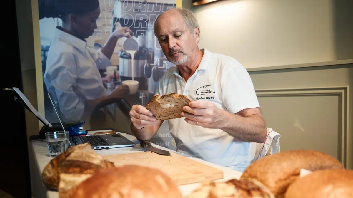 Brot- und Brötchenprüfung beim Café Lieb: Manfred Stiefel schaut sich das Brot ganz genau an, rupft ein bisschen heraus, isst das Stück, riecht daran, drückt das Brot.