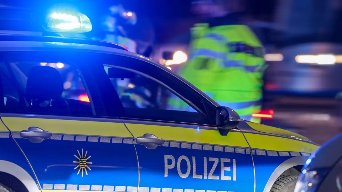 Polizei im Einsatz: Ein Polizist steht am Abend neben seinem Polizeifahrzeug mit Blaulicht. (zu dpa: «Wieder Schüsse in Berlin - Polizei sucht Täter»)