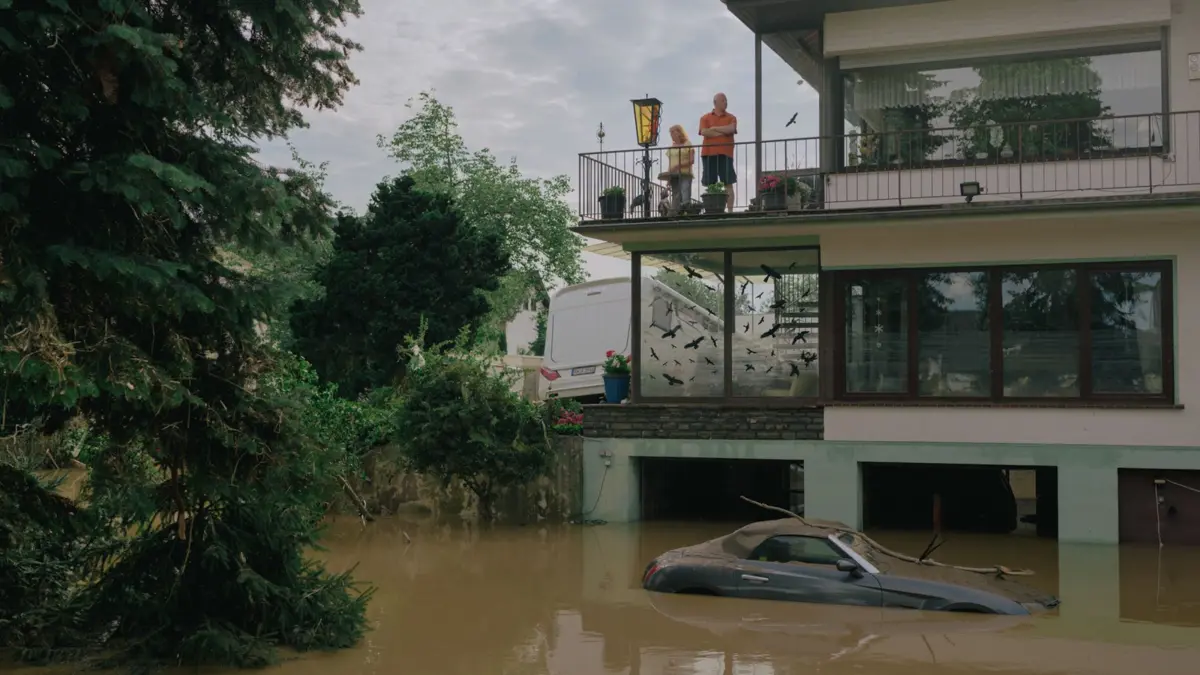 Menschen blicken von einem Balkon in Ahrweiler auf die braune Flut: ein Bild des Kollektivs Docks von der Flutkatastrophe 2021.