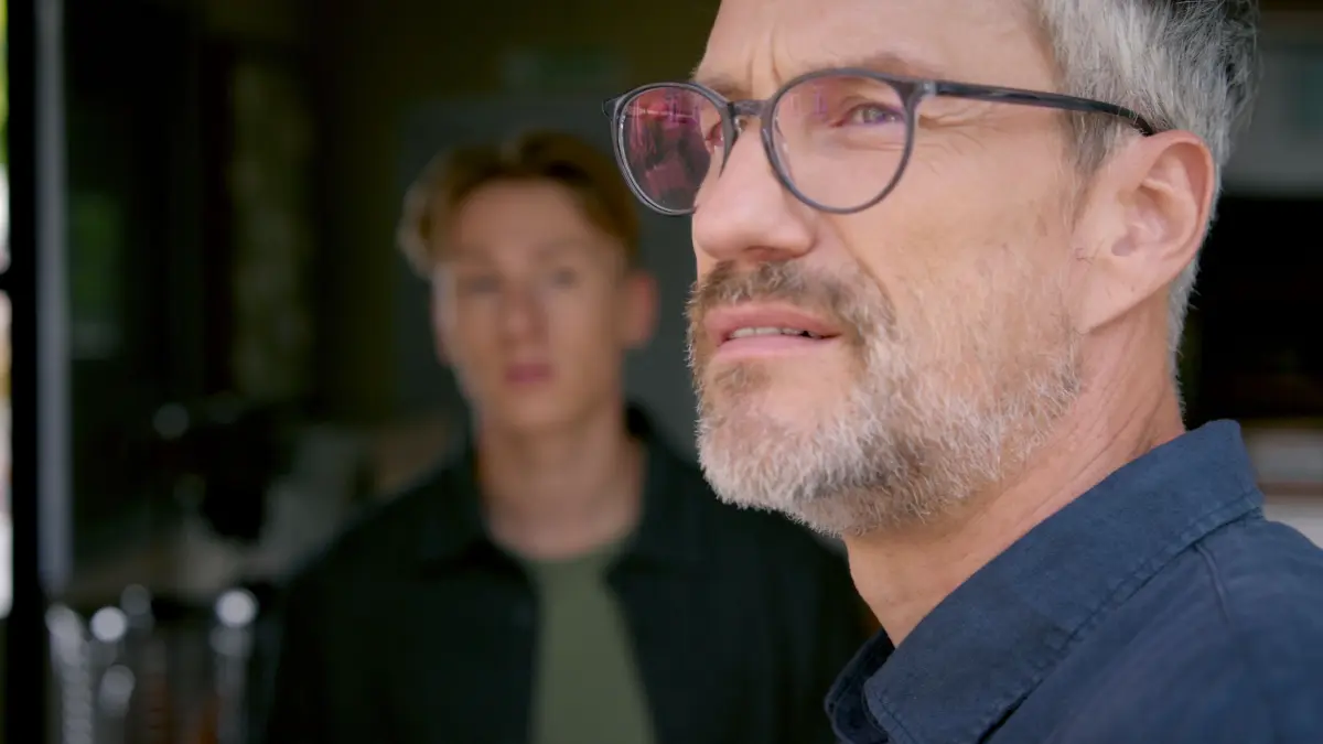 Henning (Stefan Bockelmann) gesteht Lennox (Leif Lunburg, hinten), dass er gerne viel mehr Zeit mit Romy verbringen würde.