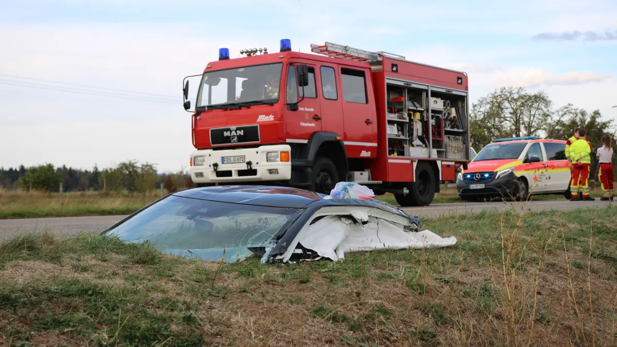Das Dach und Teile der Windschutzscheibe liegen am Fahrbahnrand.