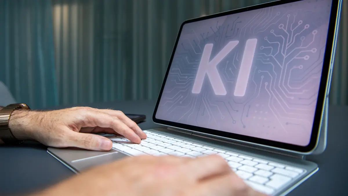 Der Schriftzug KI auf einem Tablet: ILLUSTRATION - Ein Mann nutzt KI-Assistenten auf iPad und iPhone, aufgenommen am 16.07.2025 in Berlin, Deutschland. Foto: Zacharie Scheurer || Modellfreigabe vorhanden