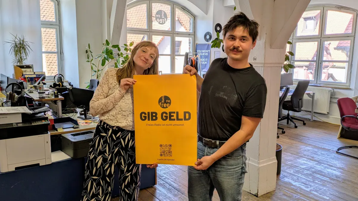 "Gib Geld": Johanna Gutmann und Erik Kasenow von Radio free FM zeigen das Spendenplakat.