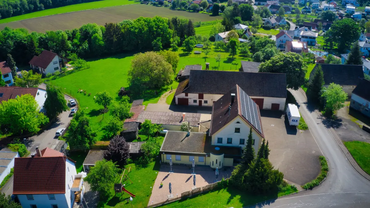 (ohne Überschrift): aus der Luft: Blick von Westen auf das Rad-Areal; im Vordergrund rechts die Gaststätte, dahinter Stadel und Stallungen