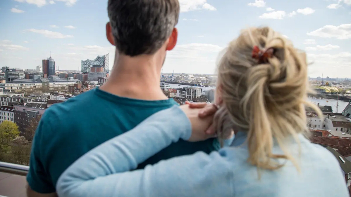 Ein Mann und eine Frau blicken von einem Balkon: ILLUSTRATION - Welche Gesten und Gesprächsangebote Trauernden als guttuend empfinden, untersucht eine Trauer-Forscherin. (zu dpa: «Kleine Gesten, die Trauernde als verständnisvoll empfinden») Foto: Christin Klose/dpa-tmn - Honorarfrei nur für Bezieher des dpa-Themendienstes +++ dpa-Themendienst +++