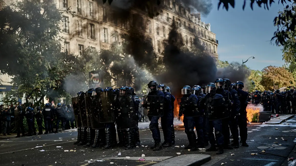 Schulproteste in Frankreich: Polizisten stehen bei Protesten gegen unterfinanzierte Schulen in Paris auf der Straße während hinter ihnen Mülltonnen brennen. (zu dpa: ««Wir haben die Schnauze voll!» - Frankreich vor Protesttag»)