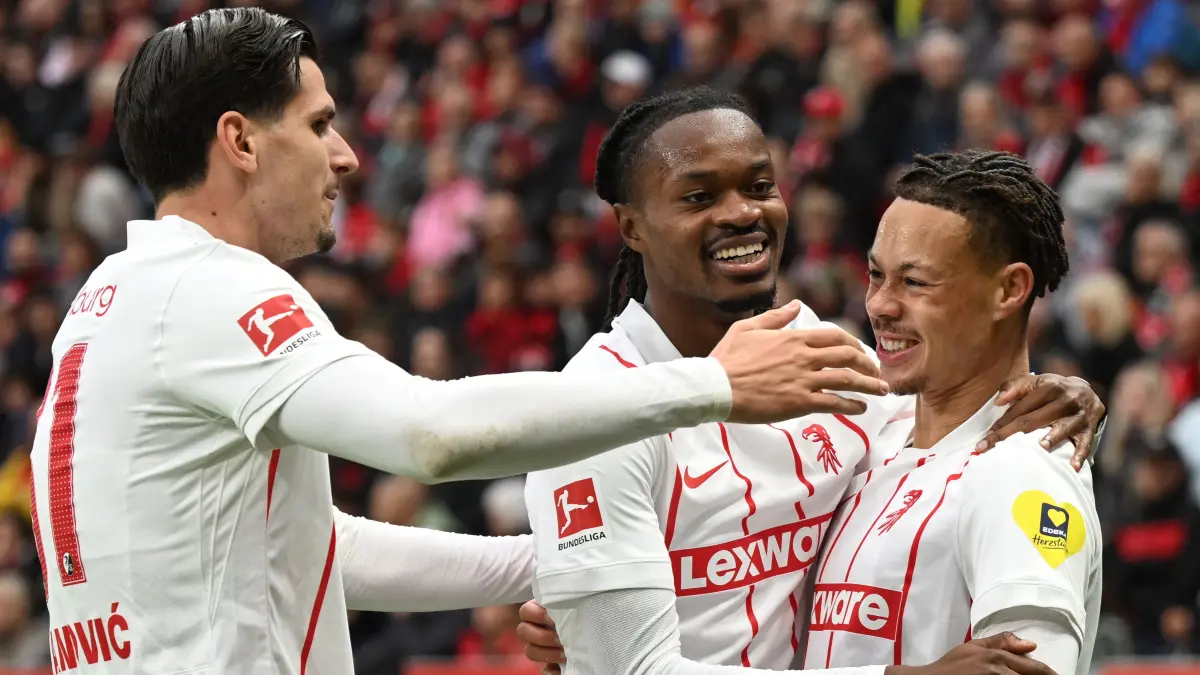 FBL-GER-BUNDESLIGA-LEVERKUSEN-FREIBURG: Freiburg's German forward #07 Derry Scherhant (R) is congratulated by Freiburg's German forward #31 Igor Matanovic (L) and Freiburg's French defender #33 Jordy Makengo (C) after scoring the 0-1 opening goal during the German first division Bundesliga football match between Bayer Leverkusen and SC Freiburg in Leverkusen, western Germany, on October 18, 2026. (Photo by INA FASSBENDER / AFP) / DFL REGULATIONS PROHIBIT ANY USE OF PHOTOGRAPHS AS IMAGE SEQUENCES AND/OR QUASI-VIDEO