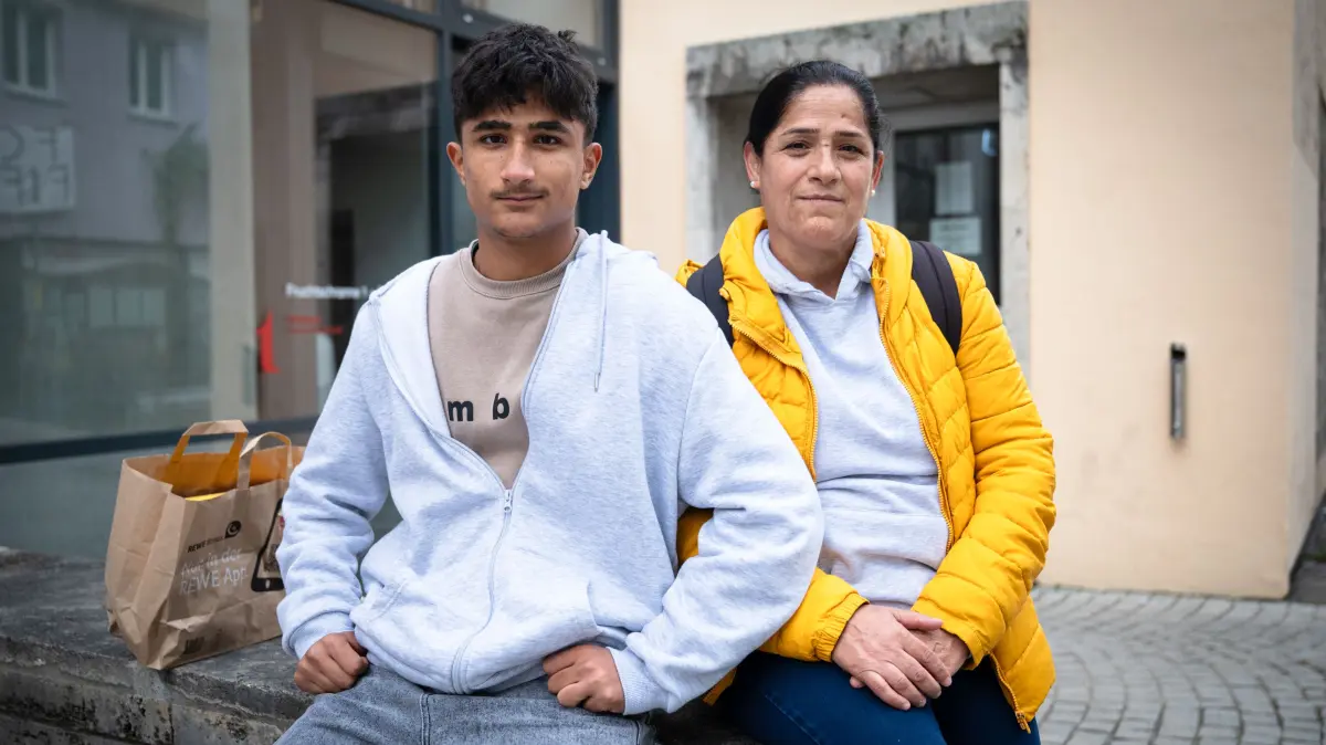 Ali und seine Mutter vor dem Ausländeramt. Ali hat gerade seine Duldung für die kommenden 3 Monate abgeholt. Wie es bei seiner Mutter weiter geht, ist noch ungewiss. In der Papiertragetasche hat Ali seine Sachen verstaut.