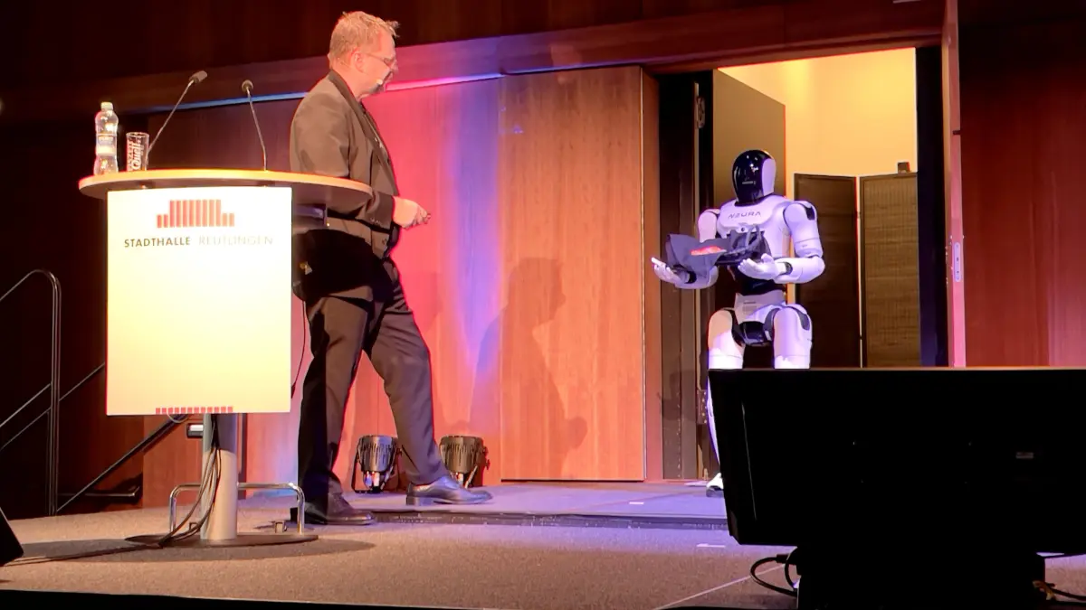 Jens Fabrowsky, COO von Neura Robotics, unterhält sich während des Metropolkongresses mit einem aus dem eigenen Haus stammenden Roboter namens Mini.