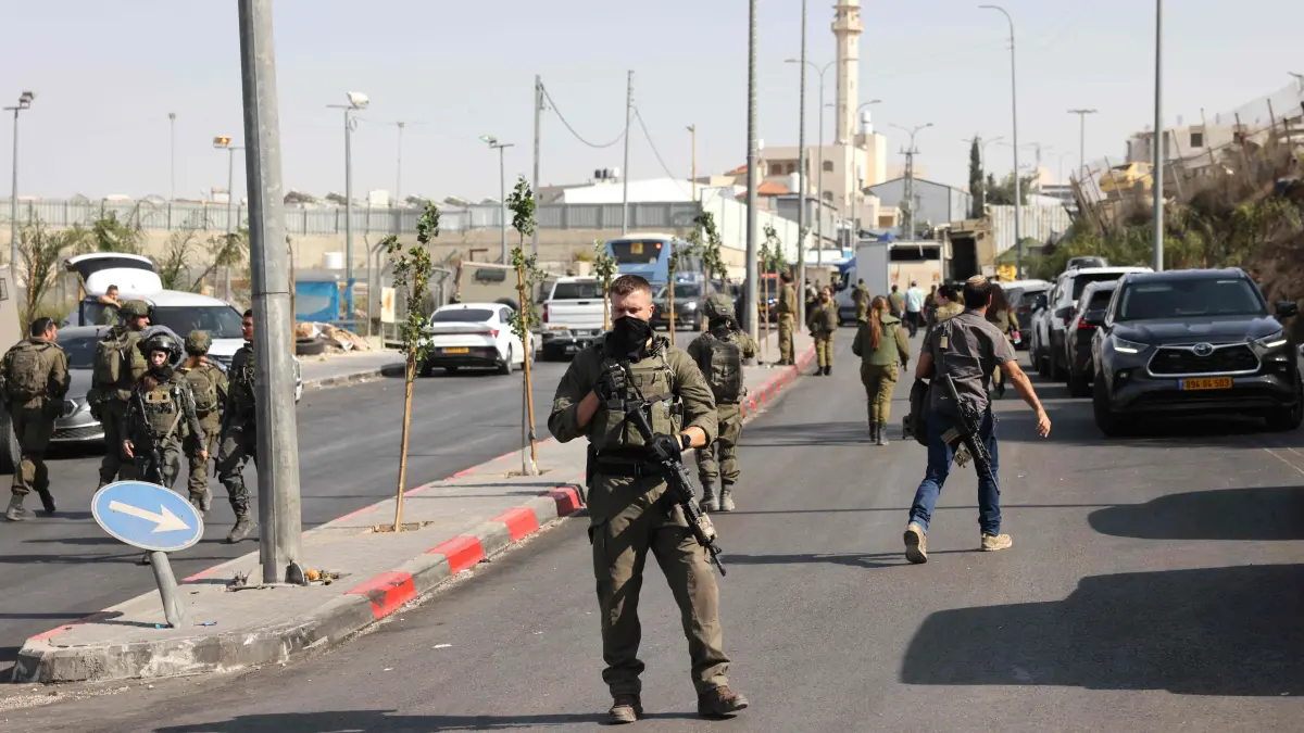 PALESTINIAN-ISRAEL-CONFLICT-WEST BANK-ATTACK: Israeli soldiers gather at the scene of an earlier fire exchange between armed Palestinians and Israeli forces following an incident at the norther checkpoint of Hebron in the Israeli-occupied West Bank on October 23, 2026. Israeli troops on October 23 shot dead two suspected Palestinian assailants in the West Bank after a shooting that left at least five people wounded, officials said. (Photo by AHMAD GHARABLI / AFP)