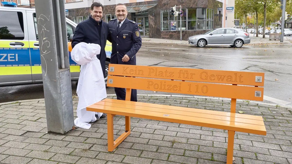 Übergabe der Orange Bank - Gewalt hat in Geislingen keinen Platz. Der Ulmer Polizeivizepräsident Askin Bingöl (rechts) und der Geislinger Oberbürgermeister Ignazio Ceffalia (links) enthüllen die Orange Bank am Stellplatz in Geislingen an der Steige. Dies Trägt die Inschrift: Kein Platz für Gewalt. Polizei 110.