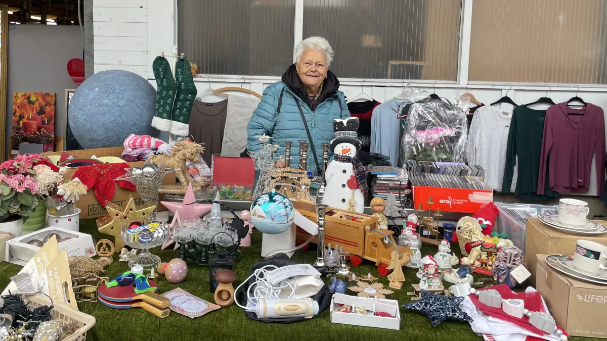 Marianne Winter hinter ihrem Flohmarktstand. Rechts von ihr stehen schön verpackte Blumen - ein vorgezogener Abschiedsgruß von einem Standnachbarn, der am eigentlichen Finaltag verhindert ist.