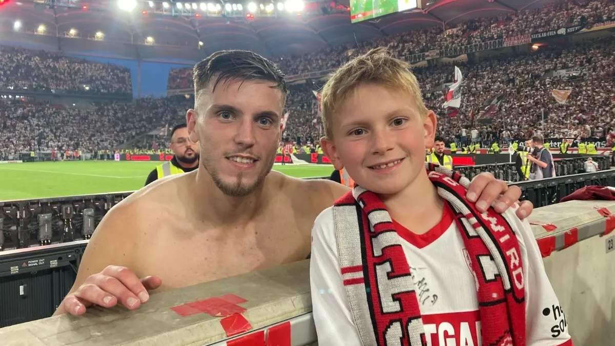 VfB-Fan-Dominik Heumesser mit dem bosnischen Nationalspieler Ermedin Demirovic nach seinem im Fernsehen auch gezeigten Plakat „Tausche Papa gegen VfB-Trikot.“