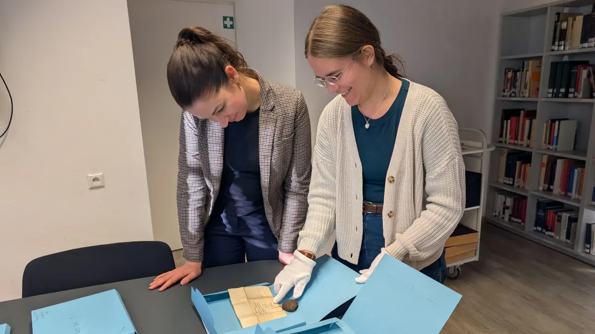 Dr. Elisabeth Fischer und Corinna Bauer vom Haller Stadtarchiv sind über zwei Urkunden gebeugt. Sie zeigen die Ähnlichkeiten, die die Schriftstücke im Haller Archiv mit jenen beiden Urkunden aufweisen, die die Stadt Halle an der Saale kürzlich angekauft hat.
