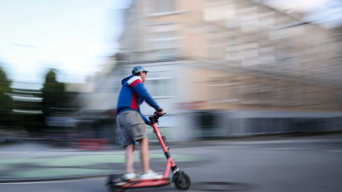 Fahrt mit E-Scooter: Ein Mann ist auf einem E-Scooter unterwegs (Aufnahme mit langer Verschlusszeit).
Manche E-Scooter fahren schneller als erlaubt. (zu dpa: ««Schockierende Bilanz» - Polizei stoppt getunte E-Scooter»)